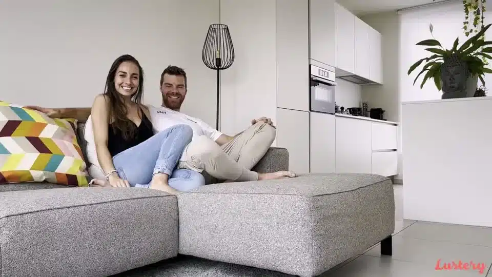 Un couple souriant assis sur un canapé, image de la plateforme Lustery